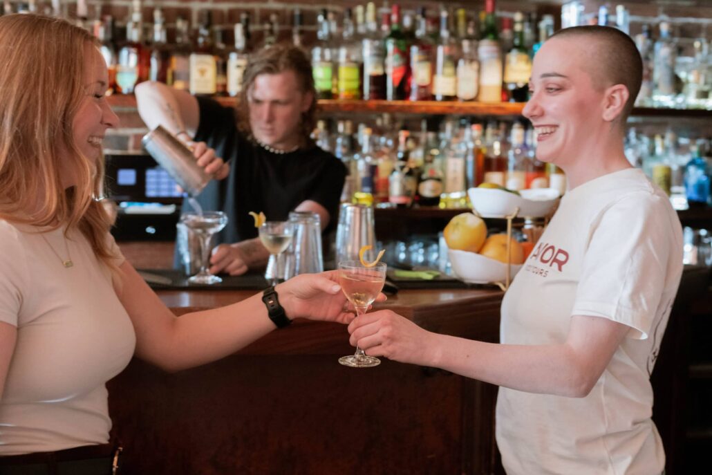 savor-seattle-tours_tour-bartender-cocktail-handing-drink Savor Seattle Tours Tour Bartender Cocktail Handing Drink